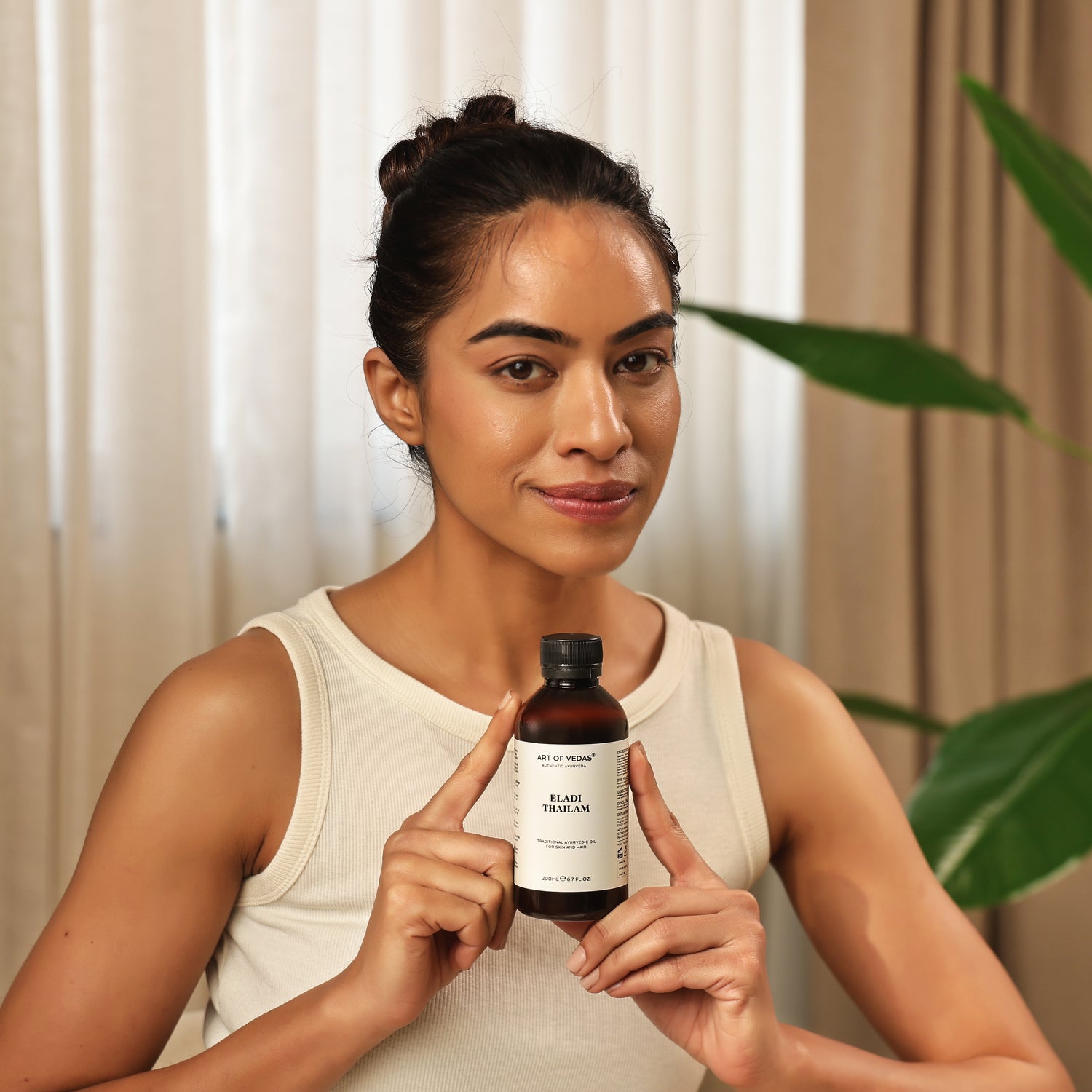 Art of Vedas Eladi Thailam - Woman Holding Authentic Ayurvedic Skin Care Oil for Complexion and Skin Nourishment