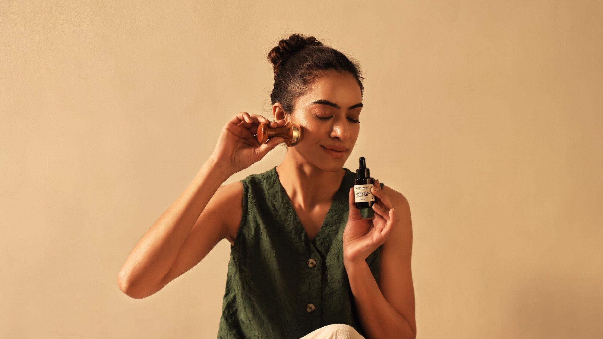 Art of Vedas Ayurvedic Face Oil beside a Kansa facial massage tool in a daily skincare ritual